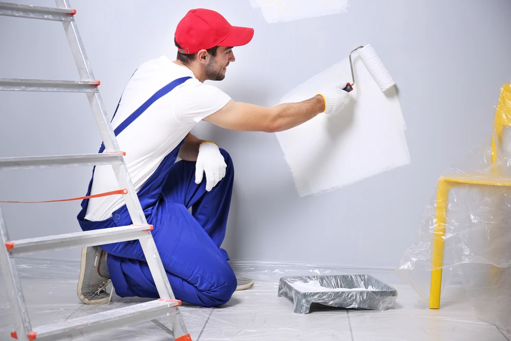 Young-worker-painting-wall-in-room